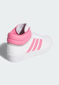 Sneaker bianco alto con colletto imbottito rosa e tre strisce rosa sui lati, appoggiato su una superficie bianca.
