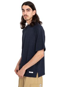 Marineblå kortærmet t-shirt i afslappet pasform, lavet af blødt stof, med en sidesplit i sømmen og et lille mærke nederst.