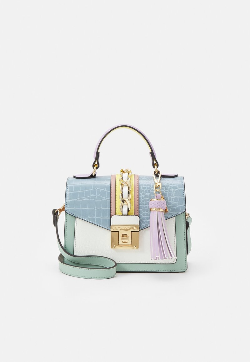 Petit sac à main pastel avec une poignée supérieure, détail chaîne dorée, fermoir avant et un charm pompon lavande sur le côté droit.