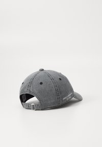 Gray denim cap featuring a curved brim, adjustable strap with metal hardware, and embroidered logo on the back panel.