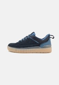 Sneaker en daim bleu marine et synthétique lisse avec une semelle texturée, des lacets ronds et une languette au niveau du talon. Présente un accent contrastant bleu clair.