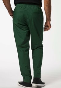 Vihreät elastiset vyötäröhousut rentoa leikkausta, joissa on kaksi takataskua ja sileä pinta. Yhdistetty mustiin korkeisiin lenkkareihin.