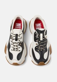 Zapatillas de cuero blancas y negras con suela gruesa, cordones multicolores, etiqueta de marca prominente y suela de goma.