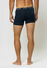 Temno modri bokserice iz mehkega materiala, ki imajo kontrastni bel elastik z logotipom U.S. Polo Assn. Prilegajoč dizajn.