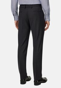 Prilagojene temno sivo hlače z gladko teksturo, z standardnim pasom, dvema zadnjima žepertoma in črnimi usnjenimi čevlji.