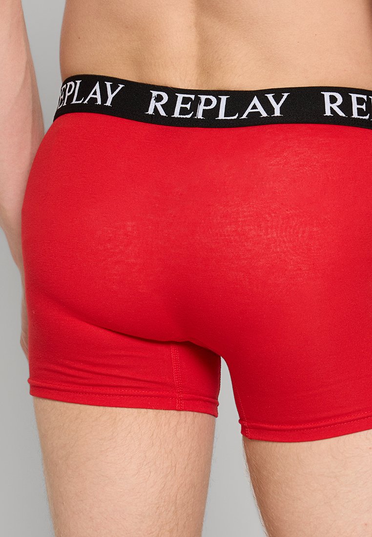 Rote Baumwoll-Boxershorts mit einem schwarzen elastischen Bund, der das Wort "REPLAY" in Weiß trägt. Glatte Textur und enganliegendes Design.