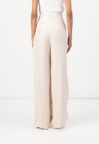 Pantalones de pierna ancha en lino beige claro, con una cintura alta y un diseño minimalista. Presenta dos bolsillos traseros y una textura suave.