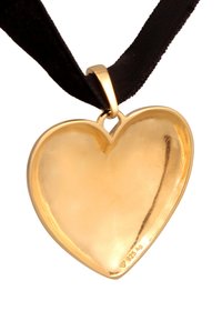 Goldfarbener herzförmiger Anhänger mit einer glatten, glänzenden Oberfläche, der an einem schwarzen Band befestigt ist. Enthält ein Stempelsymbol.