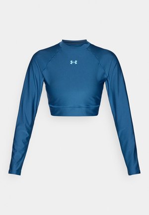 Sinine pika varrukaga lühike särk, mis on valmistatud siledast ja venivast kangast. Omaduseks kõrge kaelus ja raglaanvarrukad. Under Armouri logo hele sinises värvitoonis.