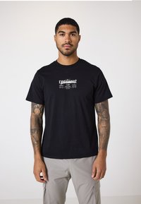 Camiseta de algodón negra con texto impreso en blanco "resilient" y diseño gráfico. Manga corta y escote redondo. Ajuste casual.