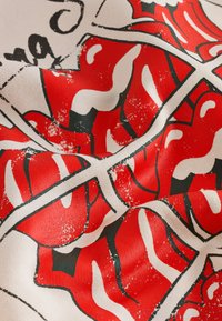 Rött och vitt texturerat tyg med en kraftfull läppdesign med svarta konturer, vilket skapar en livfull kontrast mot en ljus bakgrund.