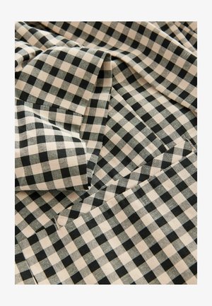 Svart och beige gingham tyg med ett rutmönster, tillverkat av texturerat material, vikt för att visa djup och dimensjonalitet.