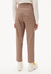 Rutiga byxor i rosa, beige och lila. Hög midja med två bakfickor. Kombinerade med vita sneakers och gula snören.