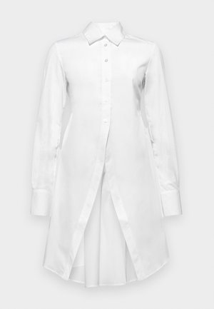 White long-sleeve shirt dress made of smooth fabric, featuring a button front, pointed collar, and an asymmetrical hem with side slits.