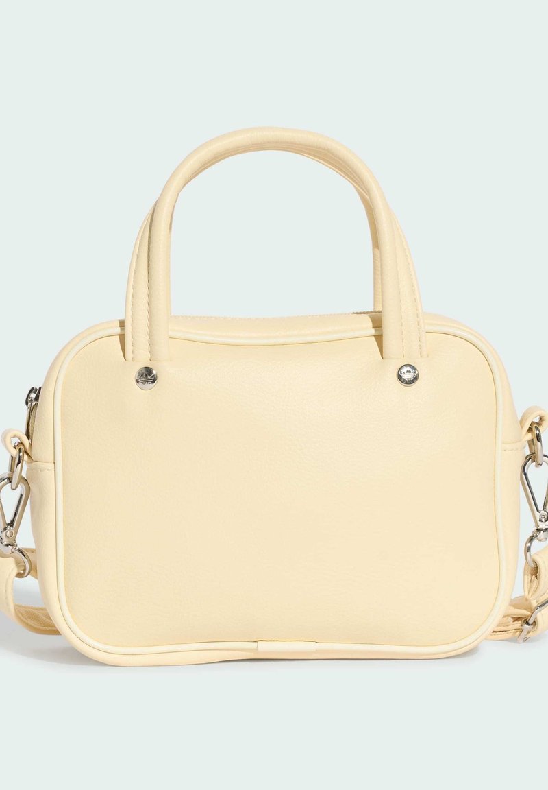 Piccola borsa rettangolare in pelle color crema con doppi manici superiori e tracolla removibile su sfondo pallido.