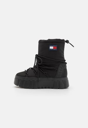 Schwarzer Winter-Hochschaftstiefel mit dicker Sohle, gewickelten Schnürsenkeln, verstellbarem Knöchelriemen und einem Tommy Jeans Logo-Patch am Schaft.