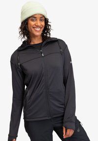 Black zip-up jacket with a ribbed texture, adjustable hood, front pockets, and branded accents. Worn with a light green beanie.