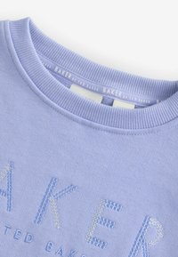 Světle fialová mikina s žebrovaným kulatým výstřihem a vyšitým nápisem "BAKER" v několika odstínech modré. Měkká textura, ležérní design.