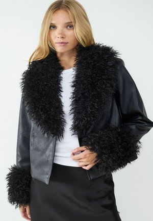 Schwarze Kunstlederjacke mit einem flauschigen schwarzen Kunstfellkragen und -manschetten, im taillierten Design und körpernahen Schnitt.