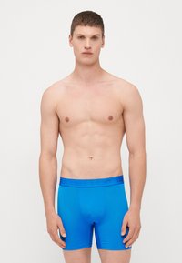 Μπλε μποξεράκια από λείο ύφασμα με εφαρμοστή σχεδίαση. Διαθέτουν ζώνη με ανάγλυφο λογότυπο της μάρκας. Απλό, μονόχρωμο.