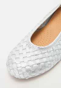 Ballet flat argent, tissé, avec un bout rond et une texture intérieure subtile dotée de perforations pour la respirabilité. Fini lisse et réfléchissant.