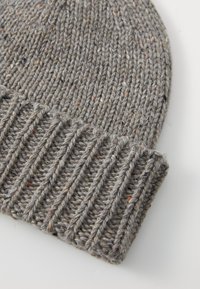 Bonnet en tricot gris fait de fil texturé avec un revers côtelé, présentant des éclats de couleur à travers le tissu.