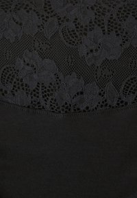 Zwarte top met een bloemenkant overlay bij de halslijn, met een gladde, rekbare stof eronder. Het ontwerp is eenvoudig en elegant.