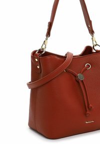 Borsa a mano in pelle rossa con texture, chiusura a coulisse, tracolla e dettagli in metallo dorato. Presenta una base piatta per maggiore stabilità.