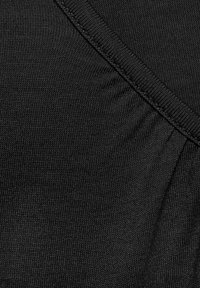 Black knit fabric with a textured surface, featuring gathered detailing along the seam. Smooth finish and subtle sheen.