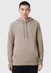 Sudadera con capucha beige, con bolsillo canguro, puños y dobladillo acanalados. Presenta un sutil logotipo bordado en el pecho. Textura suave.