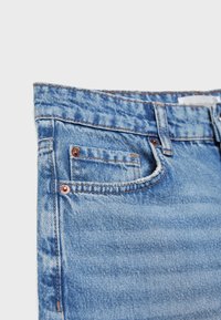 Ljusblå denimjeans med en klassisk design, fem fickor och synlig sömnad med kopparnitar. Slät textur med lätt blekning.