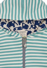 Gestreifte Kapuzenjacke in Blaugrün und Weiß. Innen hat sie einen Marineblauen Hintergrund mit Elefantenmustern. Hergestellt aus 100% Bio-Baumwolle, mit einem Reißverschluss.