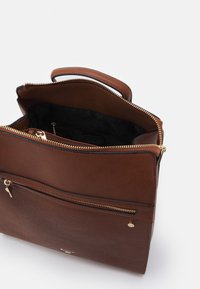 Bruine leren tas met een gestructureerd oppervlak, voorzien van een bovenste ritsluiting, een voorste ritsvak en accenten van goudkleurig beslag. De binnenkant is zwart.