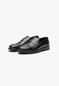 Schwarze Lederloafers mit einer glatten Oberfläche, abgerundeter Zehenpartie und einem gestickten Design über dem Rist; verfügen über eine flache, niedrige Sohle.