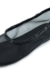 Ballerine in rete nera con suola sottile e testurizzata, caratterizzate da un bordo liscio e ritagli ovali lungo il margine per una migliore traspirabilità.
