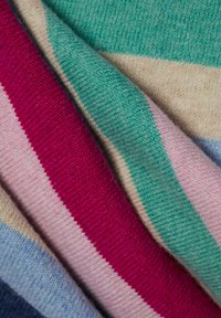 Gebreide textiel met kleurrijke strepen: levendig roze, groen, zacht beige en lichtblauw. Het materiaal heeft een textuur met een gezellige uitstraling.