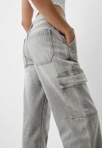 Pantalones cargo de mezclilla gris claro con un corte relajado. Presentan bolsillos a ambos lados y una cinturilla clásica. La sutil textura desvaída realza el diseño.