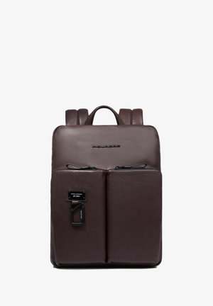 Mochila de cuero marrón con una textura suave, que cuenta con dos bolsillos frontales con cremallera, un asa superior y tirantes ajustables.