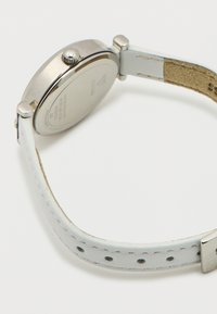 Ασημένιο ρολόι χειρός με στρογγυλό κουτί, λευκό δερμάτινο λουράκι και υφή στην πίσω πλευρά. Διαθέτει απλή κορώνα στη δεξιά πλευρά.