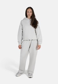 Grå hettegenser og matchende joggebukser laget av mykt stoff, med en avslappet passform, lange ermer og en justerbar hette.