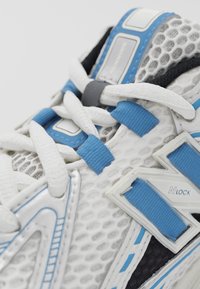 Vit mesh sneakers med blå accenter, strukturerade överdrag och NLOCK-logotyp. Snörena är vita med blå ögla.