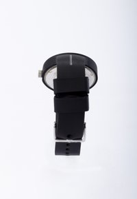 Sort analog ure watch med en rund urkasse, silikonearmbånd, sølv hardware og en hvid urskive med timeinddelinger. Enkel, moderne design.