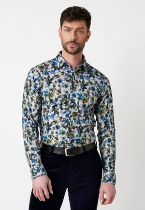 Bloemmotief shirt in het wit met blauwe bloemen en groene bladeren. Lange mouwen, knoopsluiting, met een puntige kraag en een getailleerde snit.