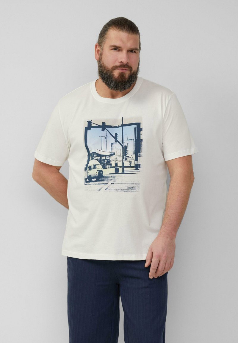White cotton t-shirt featuring a blue graphic print of a city street with traffic signals and a small car. Short sleeves, crew neck.