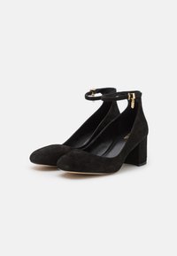 Zapatos de tacón alto de ante negro con puntera redondeada, tiras en el tobillo, tacón cuadrado y detalles de hardware dorado. Forro interior suave.