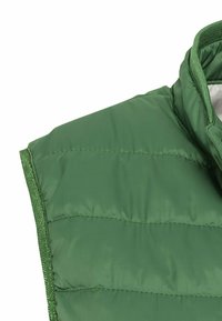 Gilet matelassé vert avec un col haut, un design à quilté horizontal et une texture lisse et brillante avec des bordures contrastées.