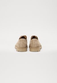 Beige suede sko med strukturert finish, rund form og gummisåler. Designet har en hælakkent for økt stabilitet.