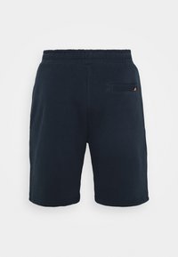 Shorts à taille élastique noire avec une petite poche arrière comportant un détail de logo visible en orange et rouge.