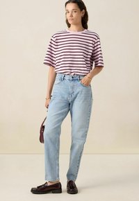 T-shirt à rayures rose clair avec des manches courtes, associé à un jean taille haute bleu clair et des mocassins bourgogne foncé. Design simple et coupe.