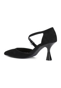 Zapato de tacón de ante negro con punta afilada, una correa decorativa en el tobillo y un tacón de aguja brillante y acampanado.